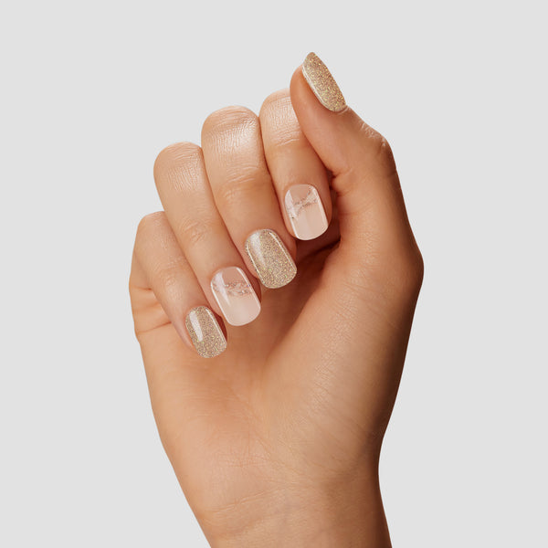 Ivory & glittered champagne gel nail strips featuring iridescent glitter, asymmetrical french tips, and leafy accents with a double gel formula for an ultra-smooth finish.