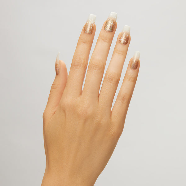 Long length, coffin shape, glossy finish. Milky white glue-on gel nails featuring ombré gold glitter and snowflake accents.
