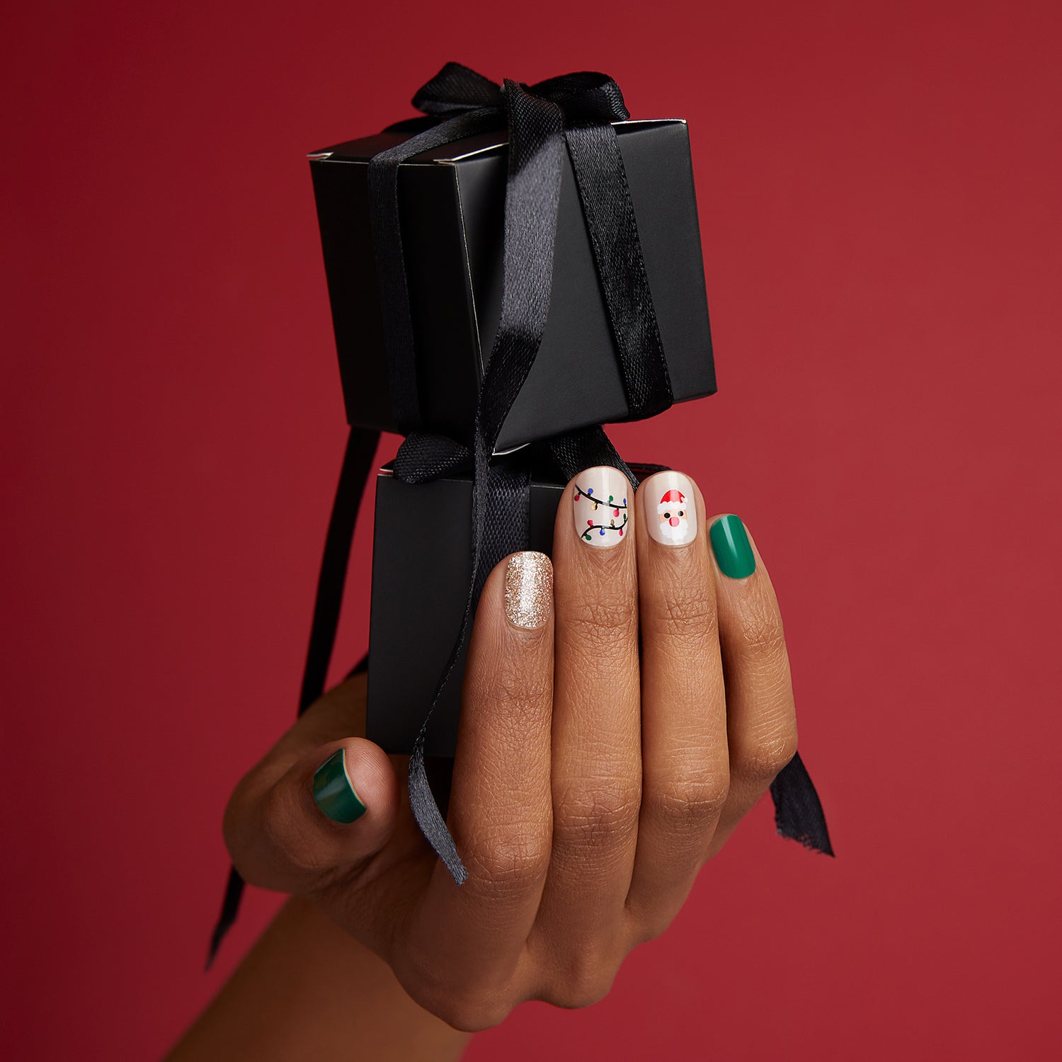 Solid green, solid sheer nude, glittered red, and glittered champagne nail strips featuring santa & tree icons and string light accents with a glossy, high-shine finish.