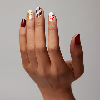 Deep red and cream nail strips featuring gingerbread, candy canes, mints, and stripes with a glossy, high-shine finish.