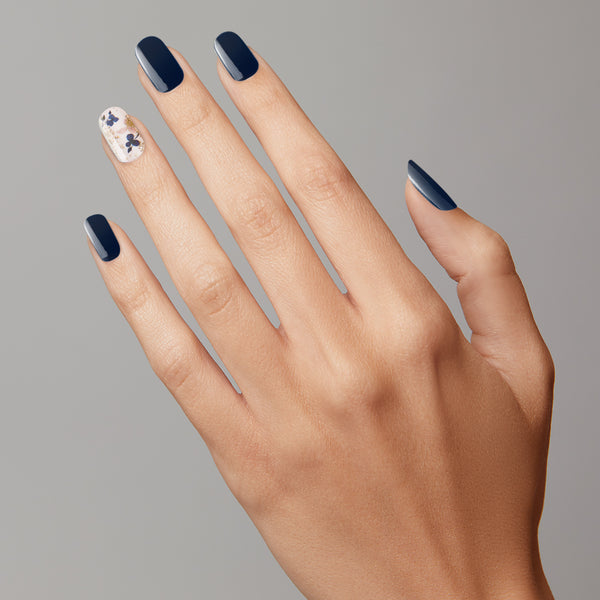 Midnight blue and ivory nail strips featuring gold foil and pressed flower accents with a glossy, high-shine finish.