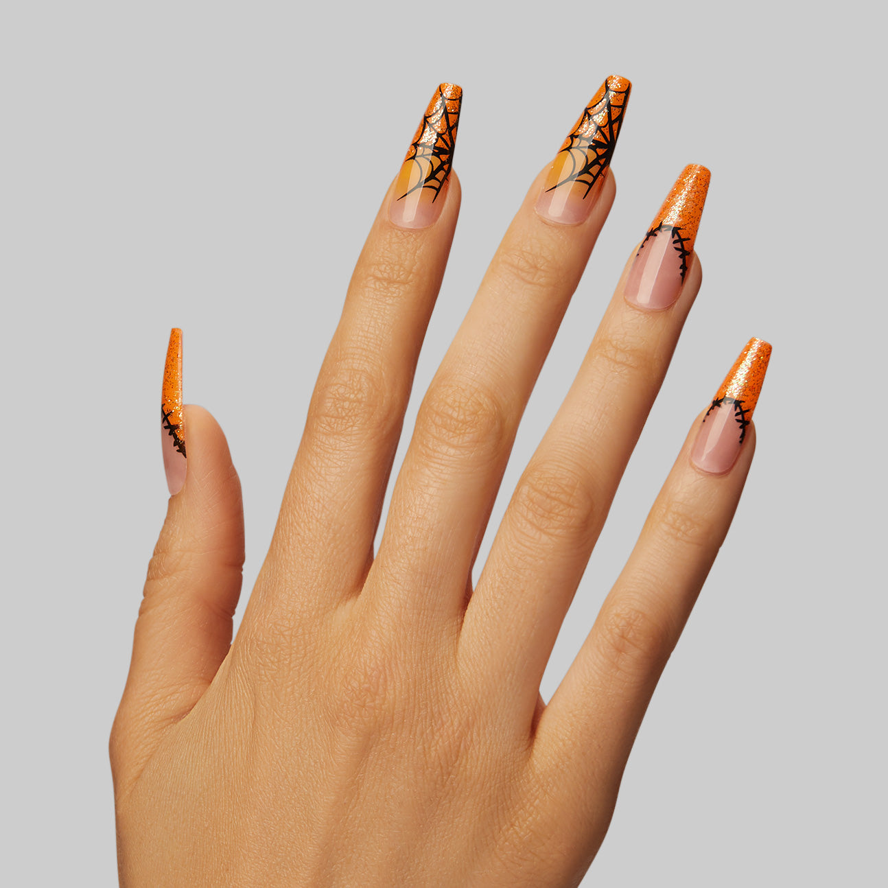  Nails that'll have them wrapped around your finger and tangled in your web by midnight. Extra long length, coffin shape, glossy finish. Sheer nude glue-on gel nails featuring bright orange french tips with stitching details, iridescent glitter, and spiderweb accents.