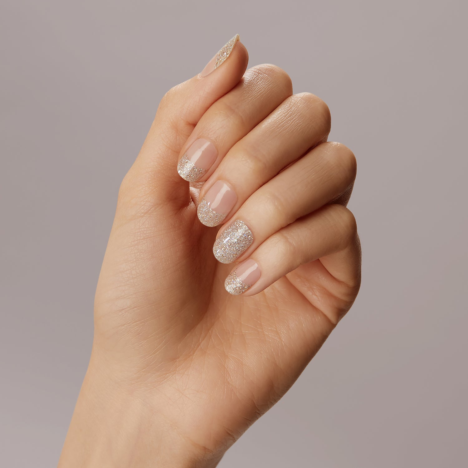 Sheer beige gel nail strips featuring iridescent champagne glitter and glittered french tips with a double gel formula with an ultra-smooth finish.