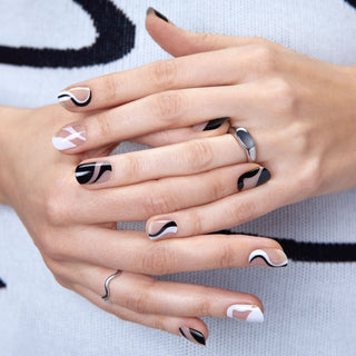 Semi-cured sheer nude gel nail strips featuring black and white wavy abstract accents and French tips with mega volume & maximum shine.