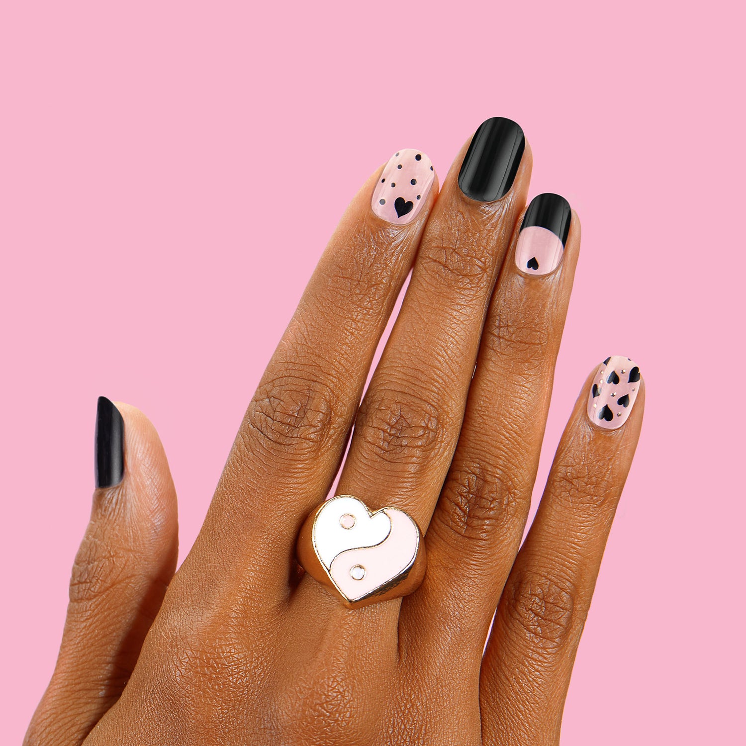 pink and black nail strips featuring a black French tip, fluttery hearts, and 3D gold detailing 