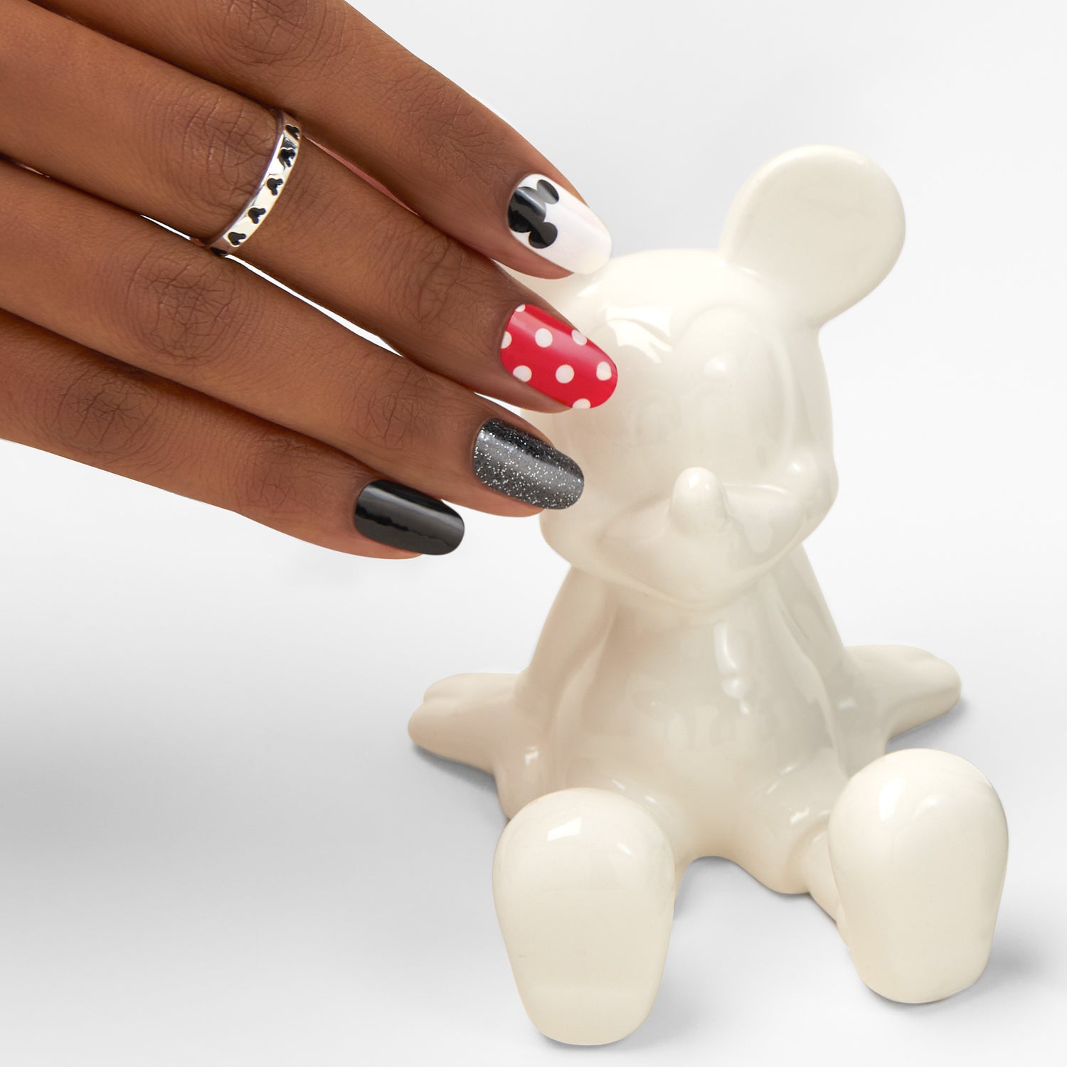 Black gel nail strips featuring red polka dots, mickey ears, and black glitter accents with a glossy, high-shine finish.  with white Mickey Mouse statue