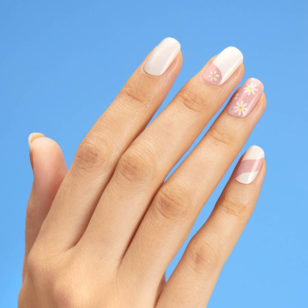 Nude and white gel nail strips featuring abstract swirls and daisy accents with a double gel formula for an ultra-smooth finish.