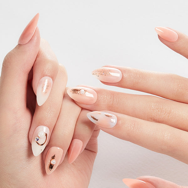 Long length, stiletto shape, glossy finish peach & pearlescent white press-on gel nails featuring iridescent glitter, rose gold foil, pearls, and gradient accents.